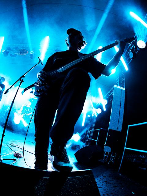 Bassist silhouetted against blue light