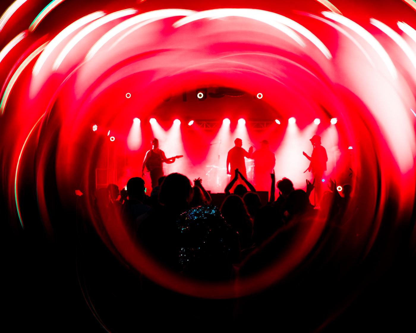 The band silhouetted in a red light swirl above the crowd